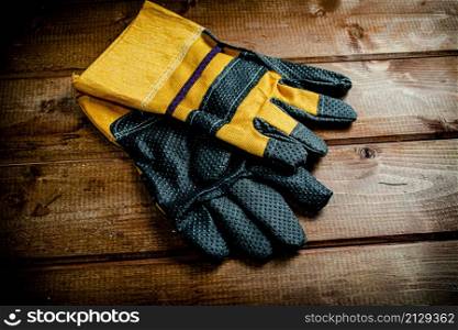 A pair of construction gloves on the table. On a wooden background. High quality photo. A pair of construction gloves on the table.