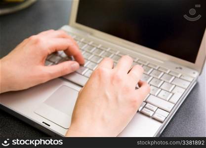 A pair of female hand using a laptop computer. Shallow depth of field with the focus on the hands.