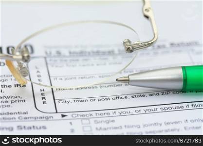 A pair of glasses and a green pen on an income tax return form