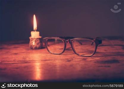 A pair of glasses next to a small candle