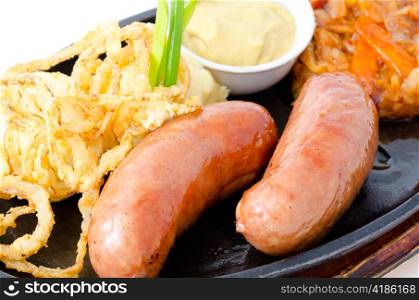 a pair of grilled frankfurters, potato, onion rings in batter and mustard