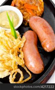 a pair of grilled frankfurters, potato, onion rings in batter and mustard