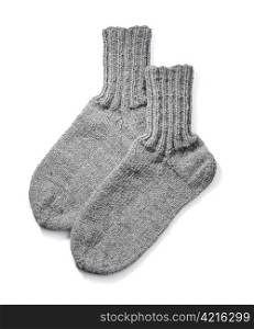 A Pair of hand-knit grey wool socks on white background with natural shadows.