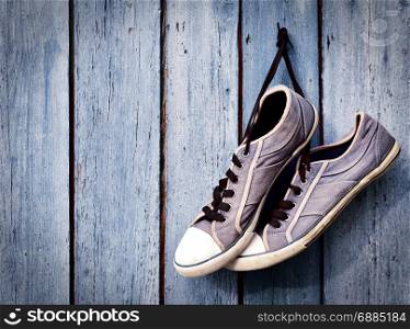 a pair of old man&rsquo;s dirty blue sneakers hanging on a wooden wall, empty space