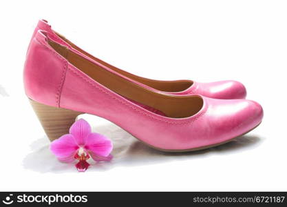 A pair of pink leather ladies shoes and a pink orchid