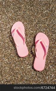 A pair of pink sandals in the sand