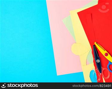 a pair of plastic scissors and colored paper for cutting figures, application and scrapbooking, copy space