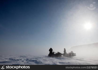 A pair of snowmobiles in a winter blizzard with blowing snow