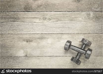 a pair of vintage iron dumbbells on a grained wood background with a copy space, digital charcoal painting effect