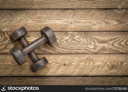 a pair of vintage iron rusty dumbbells on a grained barn wood background with a copy space