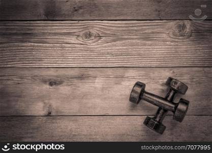 a pair of vintage iron rusty dumbbells on a grained grunge wood background with a copy space