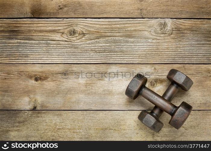 a pair of vintage iron rusty dumbbells on a weathered wood background with a copy space