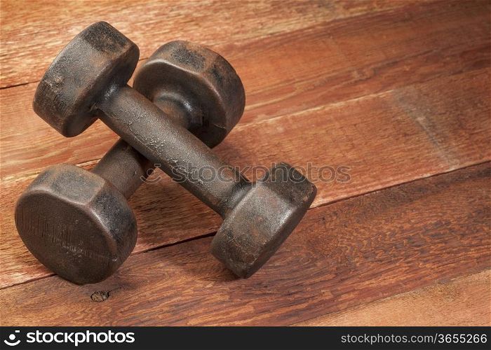 a pair of vintage iron rusty dumbbells on red barn wood background - fitness concept