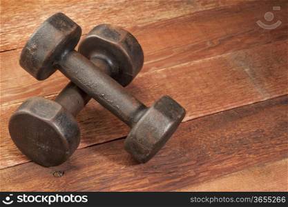 a pair of vintage iron rusty dumbbells on red barn wood background - fitness concept