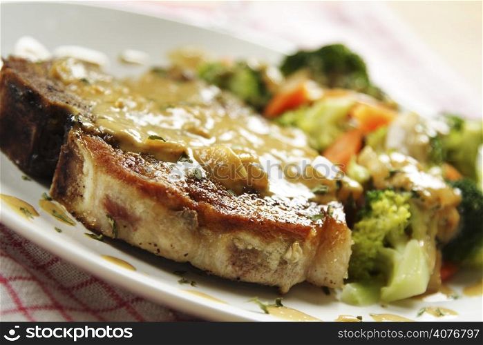 A pan fried pork chop with vegetables and coconut sauce
