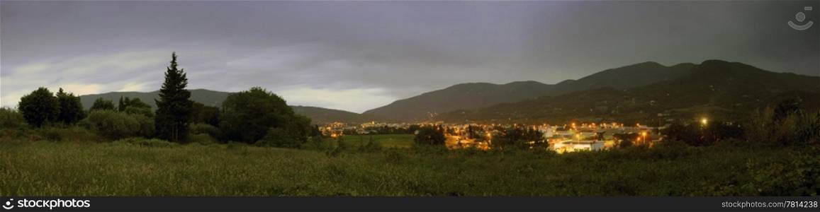 A panoramic image of the town of Nyons, Drome en Provence, in France at night, with thunderous clouds overhead