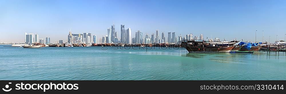 A panoramic view of the old dhow harbour in Doha, Qatar, with the West Bay skyline in the background.