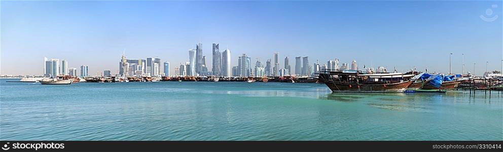 A panoramic view of the old dhow harbour in Doha, Qatar, with the West Bay skyline in the background.