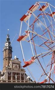 A partial view of a ferris wheel with an old historic building in the background