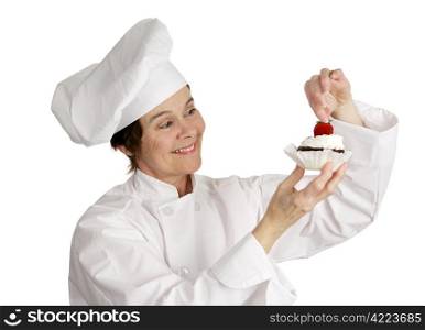 A pastry chef putting a strawberry on the top of a cheesecake tart. Isolated on white.