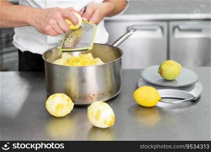 A Pastry chef’s hand grates lemon in commercial kitchen. Chef grates limes on the grater to get zest for cooking, making of pastry, healthy food, natural supplements close-up. High quality photo. A Pastry chef’s hand grates lemon in commercial kitchen. Chef grates limes on the grater to get zest for cooking, making of pastry, healthy food, natural supplements close-up.