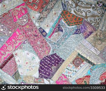 A patchwork background from India, made in the old style without regard to geometric patterns and decorated with beads and sequins
