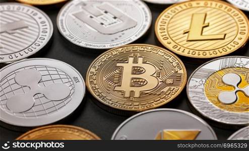 A pattern from different coins of crypto currency on a dark background. Gold and silver coins ripple, bitcoin, litecoin, ethereum, dash. Business concept. Top view. Close-up of shiny gold and silver coins on a dark background. Business and technology concept. Top view