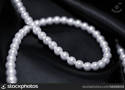 A pearl necklace on a black silk macro