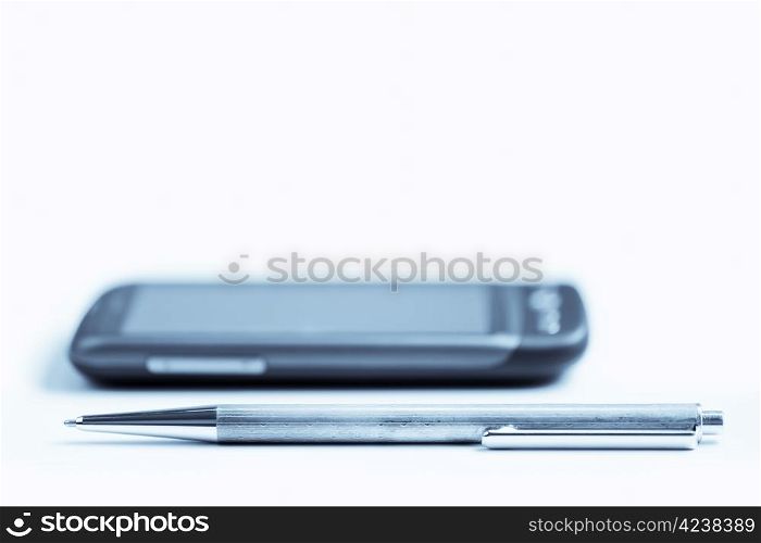 A pen and a phone on the table, focus on the pen.
