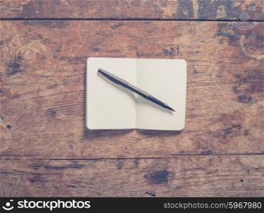 A pen and a small notepad on a wooden table