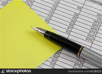 A pen and post it note on a spreadsheet with copy space