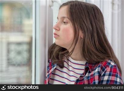 a pensive teenager girl near the window