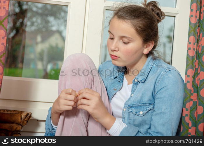 a pensive young teenager girl near the window