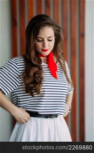 A perky girl in a striped T-shirt with a red tie.. A photo shoot of an adult girl in a pioneer tie 4169.