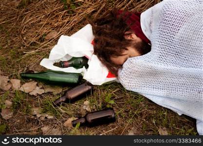 A person drunk sleeping in the ditch with liquor bottles