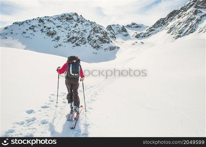 A person follows the track of ski mountaineering ascent in the alps