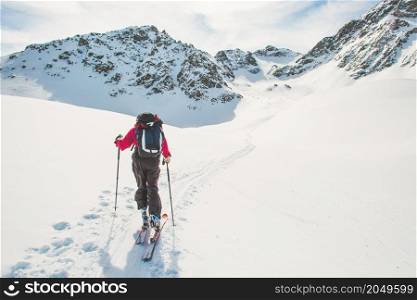 A person follows the track of ski mountaineering ascent in the alps