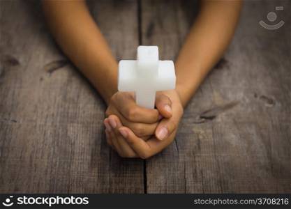 A person holding a white Religious Cross on white background