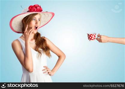 A photo of a pin-up girl in vintage hat excited of seeing a hand with the cup.
