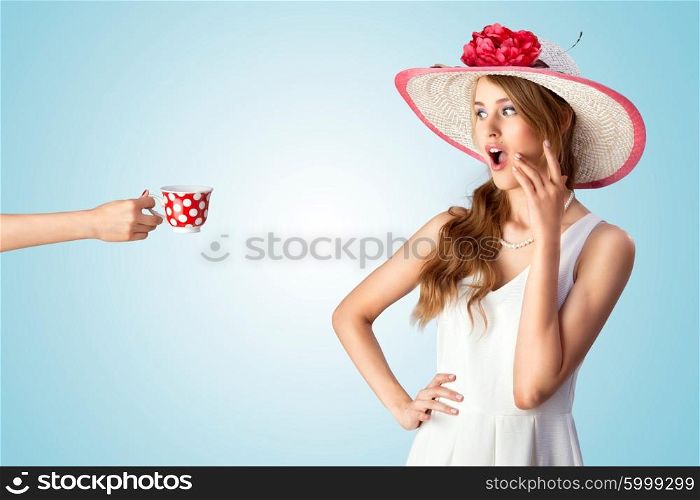 A photo of a pin-up girl in vintage hat excited of seeing a hand with the cup.