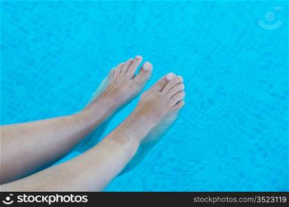 a photo of feet refreshing in swimming pool in summer