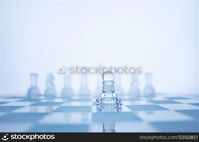 A photo of pawn standing in front of the same colour chess set.