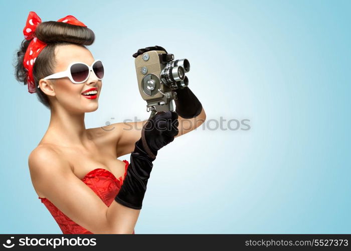 A photo of the pin-up girl in corset and gloves holding vintage 8mm camera.