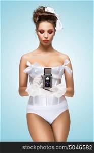 A photo of the pin-up girl in corset holding vintage camera.