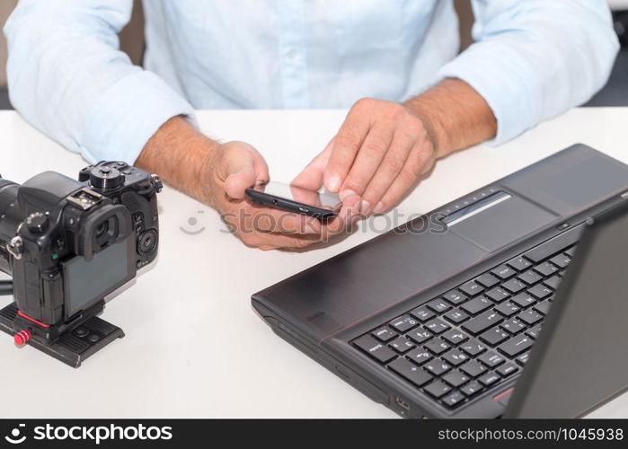 a photographer man using smartphone and laptop computer