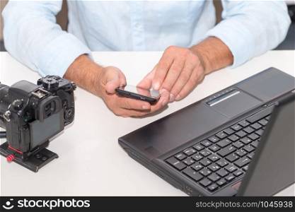 a photographer man using smartphone and laptop computer