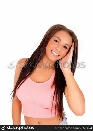 A picture of a young pretty woman standing in a pinktop, smiling and holding her head, isolated on white background.
