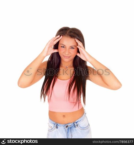 A picture of a young pretty woman standing in jeans and a pink top, with her finger at her head with headache, isolated on white background.