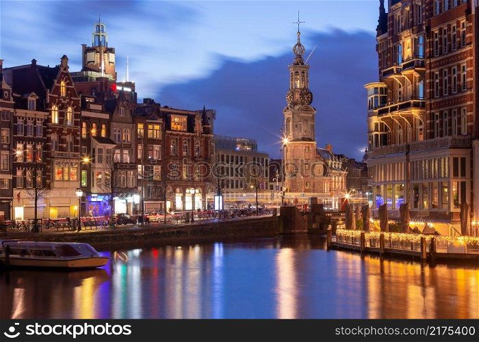 A picturesque view of the city embankment and facades of medieval fairy houses at sunset. Amsterdam. Netherlands.. Beautiful old houses on the city waterfront of Amsterdam at sunset.