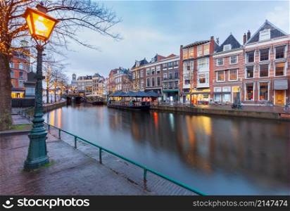 A picturesque view of the city embankment and the old facades of houses at sunset. Leiden. Netherlands.. Beautiful old houses on the city embankment of Leiden at sunset.